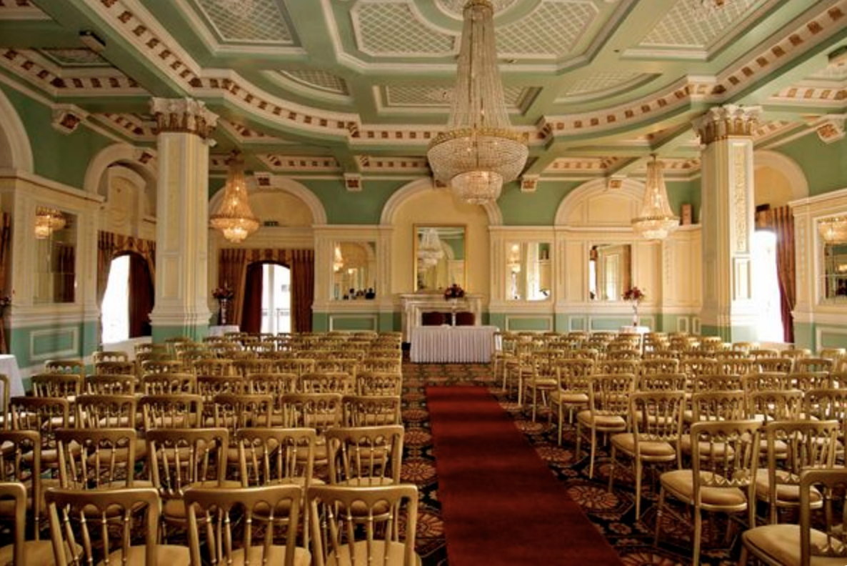 Ornate function room with decorative ceiling, columns and chandeliers