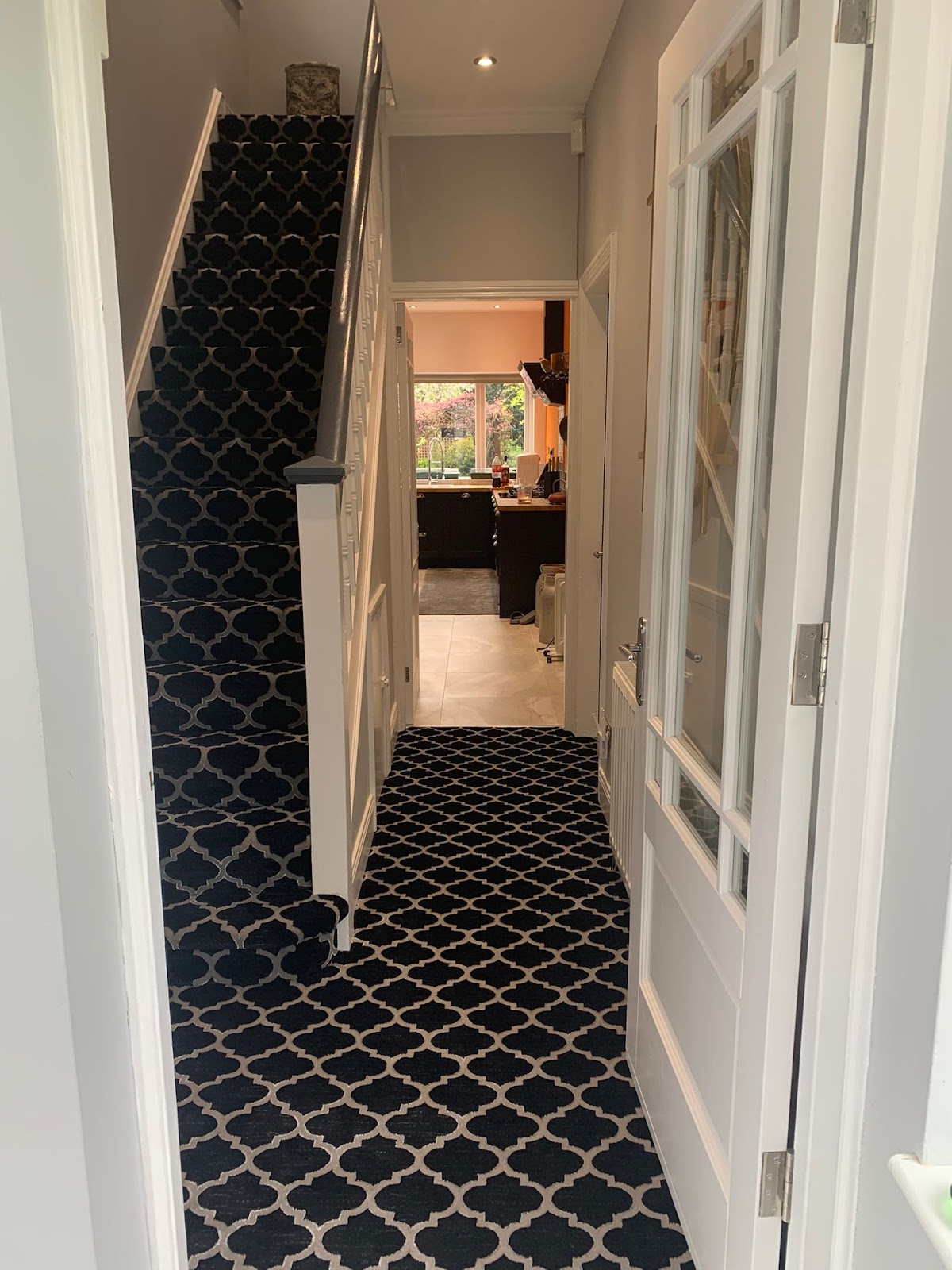 Hallway and staircase with white woodwork and patterned carpet